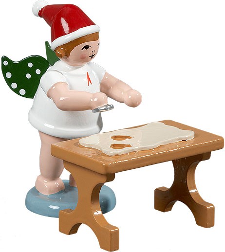 Weihnachtsengel mit Ausstechform am Tisch, mit Mütze Weihnachtsengel mit Ausstechform am Tisch, mit Mütze